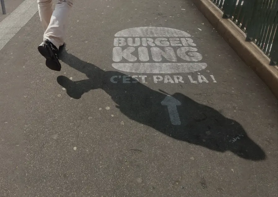 Marquage publicitaire Burger King au sol indiquant la direction d’un restaurant.